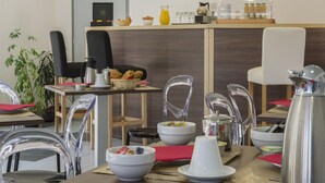 Zona pranzo in un hotel con sedie trasparenti, un angolo caffè e un orologio a parete.