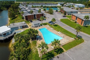 Ein Luftbild eines Resorts mit Schwimmbad, mehreren Gebäuden und einem Fluss.