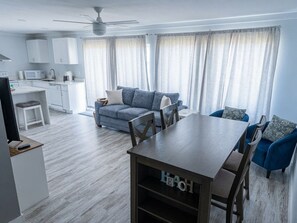 A modern living room with a dining table, sofas, and a kitchen area. - Cozy updated 2-bedroom condo with AC in serene Destin. (Destin)