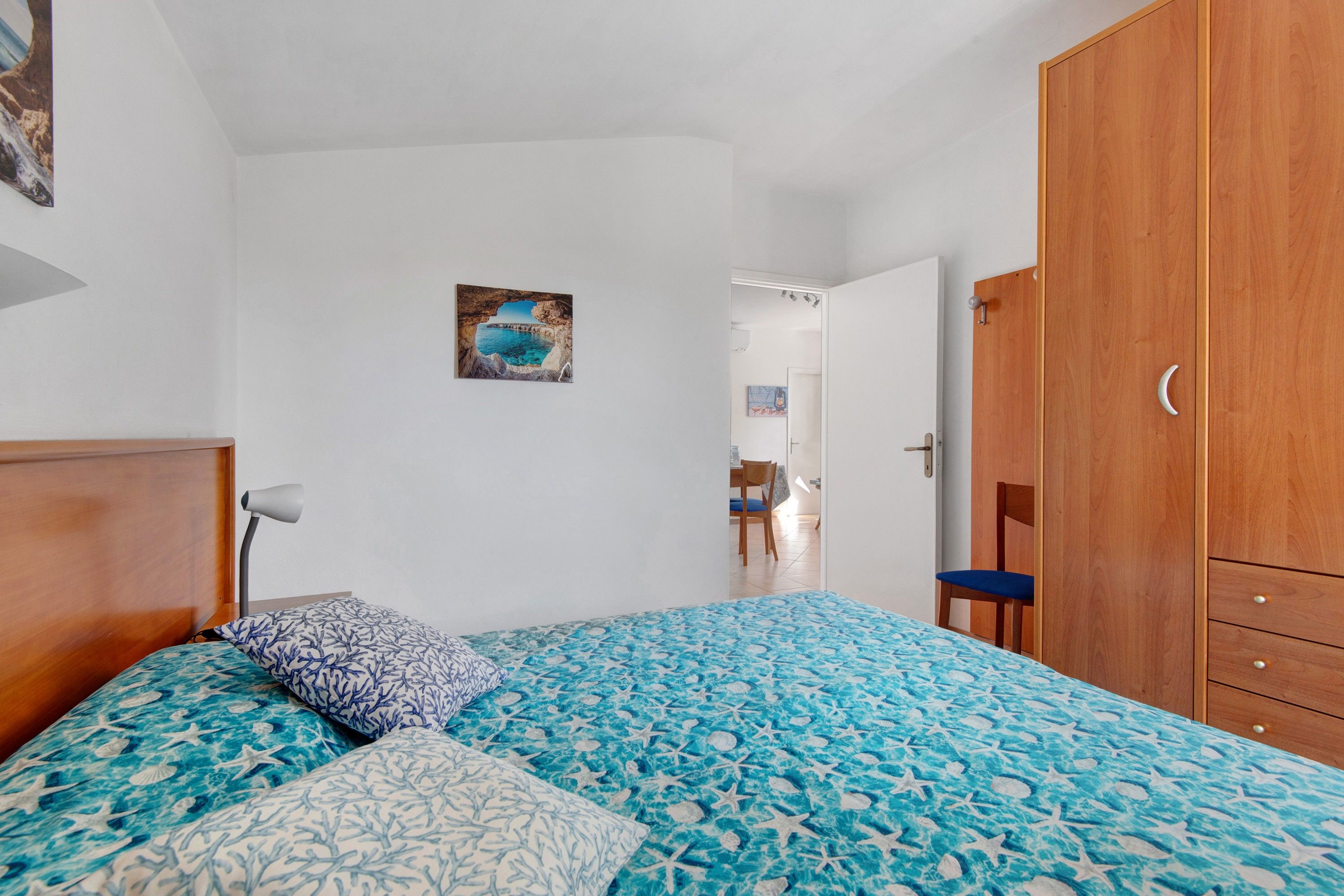 Ein Schlafzimmer mit einem Bett, einem Holzschrank und einem Bild an der Wand.