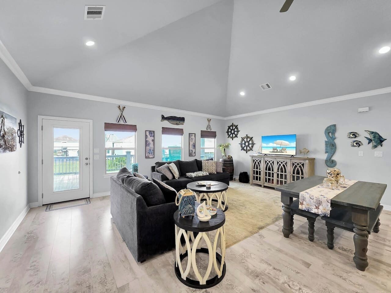 A spacious living room with a black sofa, a round coffee table, and a dining table.