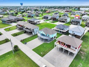 An aerial view of a residential area with houses, a water tower, and a clear sky. - On Beach Time*Prime Location (Bolivar Peninsula)