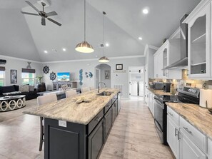 A spacious kitchen with a large island, modern appliances, and pendant lighting. - On Beach Time*Prime Location (Bolivar Peninsula)