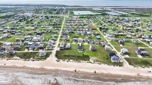 Vue aérienne d’un quartier résidentiel situé sur la côte, avec des maisons, une plage et un château d’eau.