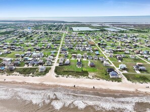 An aerial view of a coastal residential area with houses, a beach, and a water tower. - On Beach Time*Prime Location (Bolivar Peninsula)