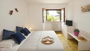 Un dormitorio con cama, mesita de noche, televisor y ventana con vistas.