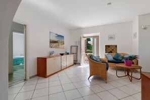 A spacious living area with a sofa, a dining table, and a kitchen area with cabinets.