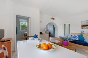 A modern kitchen with a dining area, a TV, and a view of the outdoors.