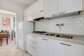 Una cucina moderna con mobili bianchi, un lavello in acciaio inossidabile e un fornello a gas.