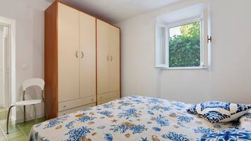 Una camera da letto con un letto, un armadio, una sedia e una finestra vista verde.