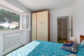 A bedroom with a bed, a wardrobe, a radiator, and a window.