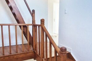 Una escalera de madera con barandilla y una puerta al final.
