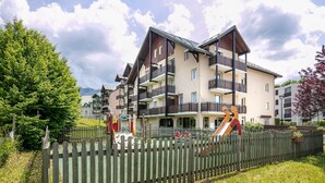 A multi-story building with balconies, a playground, and a wooden fence. - Quiet Alpine Stay Near Vercors (Villard-de-Lans)