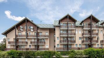 A multi-story residential building with balconies, satellite dishes, and a parking lot.