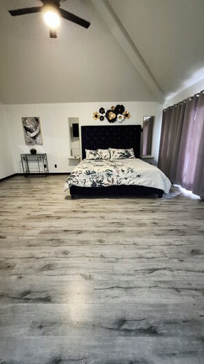 A spacious bedroom with a large bed, a ceiling fan, a wall-mounted artwork, and a small table with a vase. - BIG 5BR Home - Pets OK - RV Parking (Horizon City)