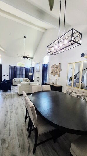 A spacious living area with a large round table, a ceiling fan, and a modern chandelier. - BIG 5BR Home - Pets OK - RV Parking (Horizon City)