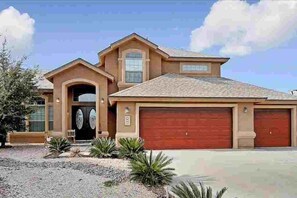 A two-story house with a red garage door, a front entrance with a glass door, and a small porch area. - BIG 5BR Home - Pets OK - RV Parking (Horizon City)