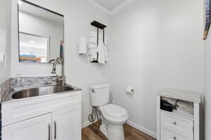 A bathroom with a sink, toilet, and a small cabinet with towels. - Beach & Bay Escape | Prime Mission Spot (San Diego)