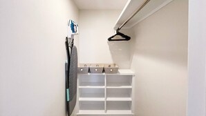 Ein schmaler begehbarer Kleiderschrank mit weißen Regalen und Platz zum Aufhängen.
