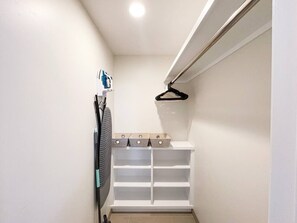 Ein schmaler begehbarer Kleiderschrank mit weißen Regalen und Platz zum Aufhängen.