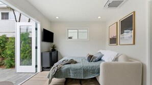 Une chambre à coucher avec un lit, une télévision, un canapé et une fenêtre.