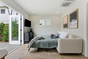 Ein Schlafzimmer mit einem Bett, einem Fernseher, einem Sofa und einem Fenster.