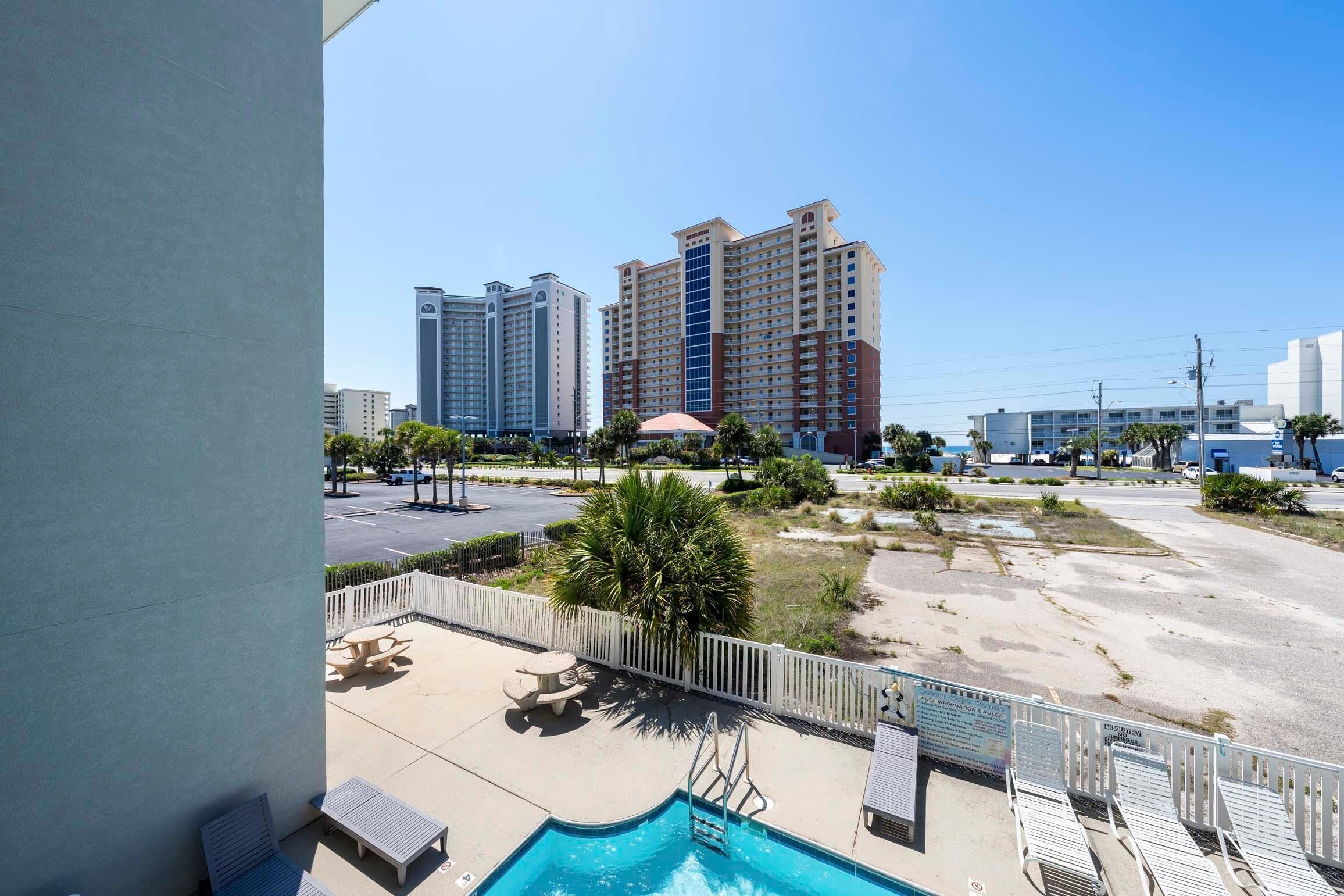 A hotel with a pool, outdoor seating, and a view of high-rise buildings.