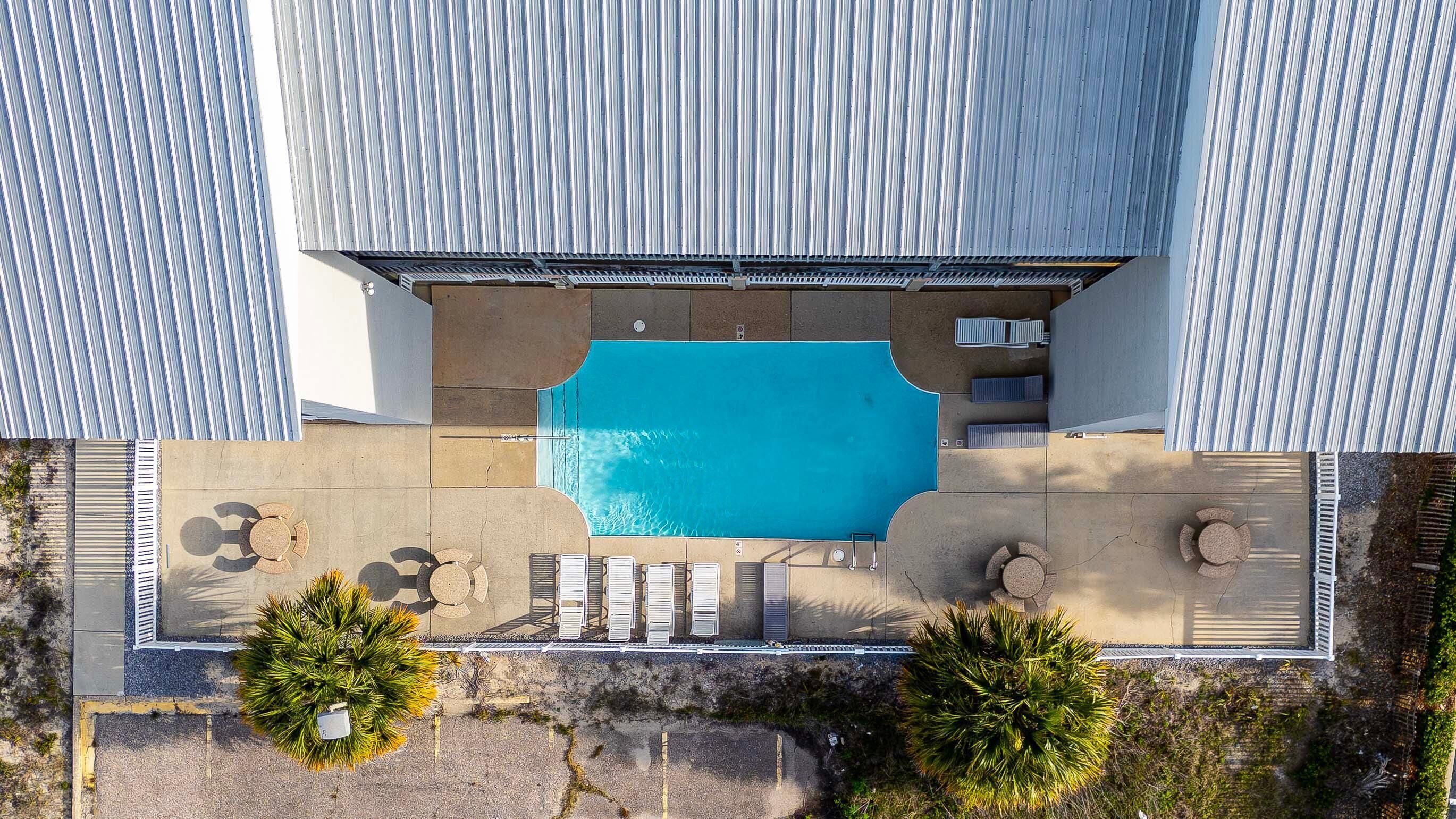 Ein Luftbild von einem Schwimmbecken mit Liegestühlen und einer überdachten Sitzgelegenheit.