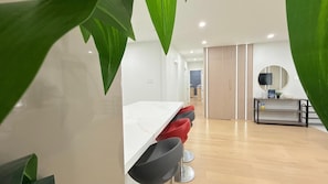 Un intérieur moderne avec un comptoir blanc, des tabourets de bar rouges et noirs, un plancher en bois et une cloison à rayures.
