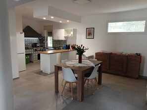 A modern kitchen with a central island, white chairs, and a dining table with a vase of flowers. - Country cottage, just 5 minutes from the sea, ideal for families groups (Ribera)