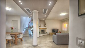 A living room with a fireplace, a dining area with a table and chairs, and a staircase leading to another level.