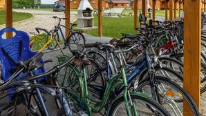 Ett överbyggt område för cykelparkering med plats för flera cyklar, en grill och en paviljong av trä.