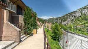 A narrow pathway flanked by buildings with balconies, leading to a mountainous landscape. - Spacious Alpine Triplex With Terrace (Guillaumes)