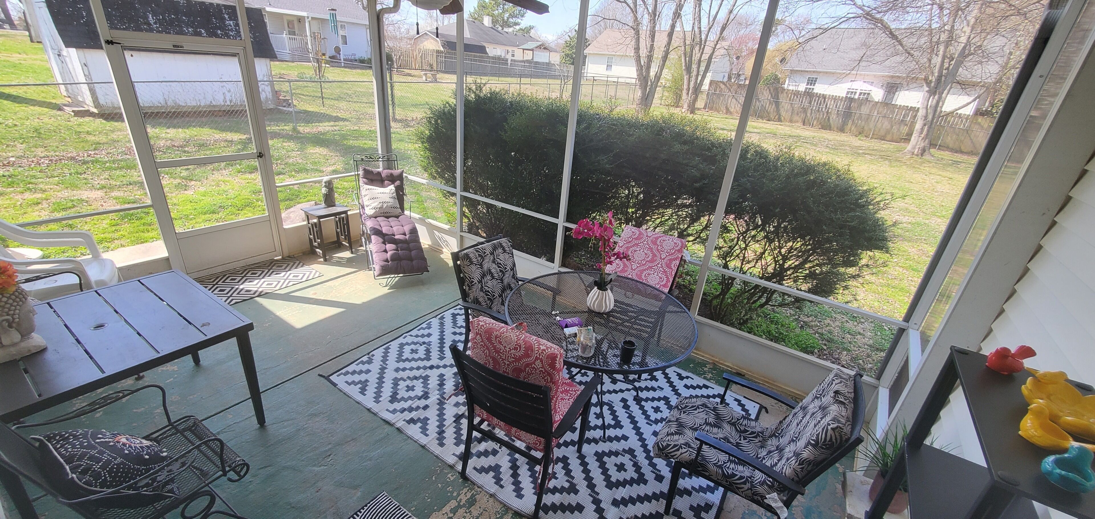 A sunroom with a cushioned bench, a small table, and a chair.