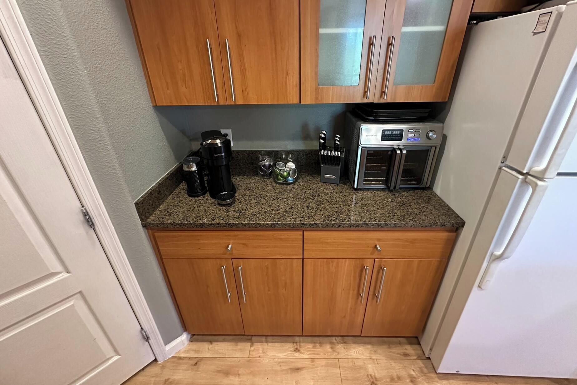 A kitchen with wooden cabinets, a coffee maker, a toaster, and a refrigerator.