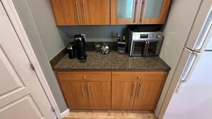 Eine Küche mit Holzausstattung, einer Kaffeemaschine, einem Toaster und einem Kühlschrank.
