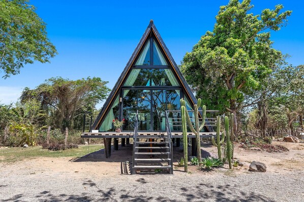 A triangular glass-roofed structure with a wooden deck and a ladder leading up to it.