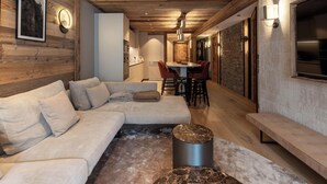 Una sala moderna con un sofá modular, un comedor y una cocina al fondo.