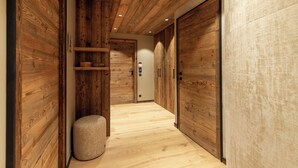Un pasillo con paneles de madera, un otoman redondo y una puerta con panel de control.