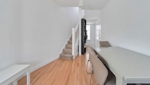 A hallway with a staircase, a white bench, and a white table. - Hounslow Hideaway Cottage (Hounslow)