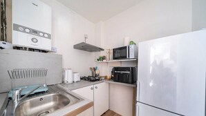 A compact kitchen with a stainless steel sink, a microwave, a built-in oven, and a refrigerator. - Hounslow Hideaway Cottage (Hounslow)