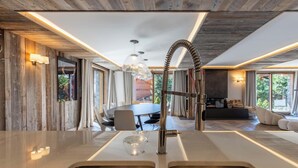 A modern kitchen with a central island, stainless steel appliances, and a dining area with a round table and chairs. - Flocon - Ours Rouge: an exceptionally spacious apartment with a jacuzzi (Les Allues)