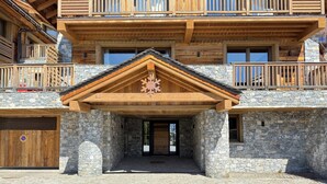A multi-story wooden building with stone walls, a covered entrance, and balconies. - Flocon - Ours Rouge: an exceptionally spacious apartment with a jacuzzi (Les Allues)