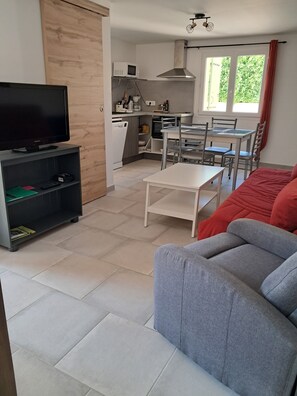 A modern living room with a flat-screen TV, a grey sofa, and a dining area with a table and chairs. - New on Abritel: A recently built vacation rental with a pool (Vaison-la-Romaine)