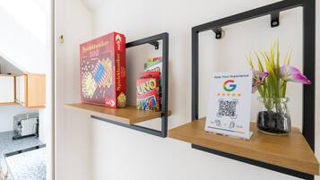 A shelf with board games, a QR code for rating experience, and a vase with flowers.
