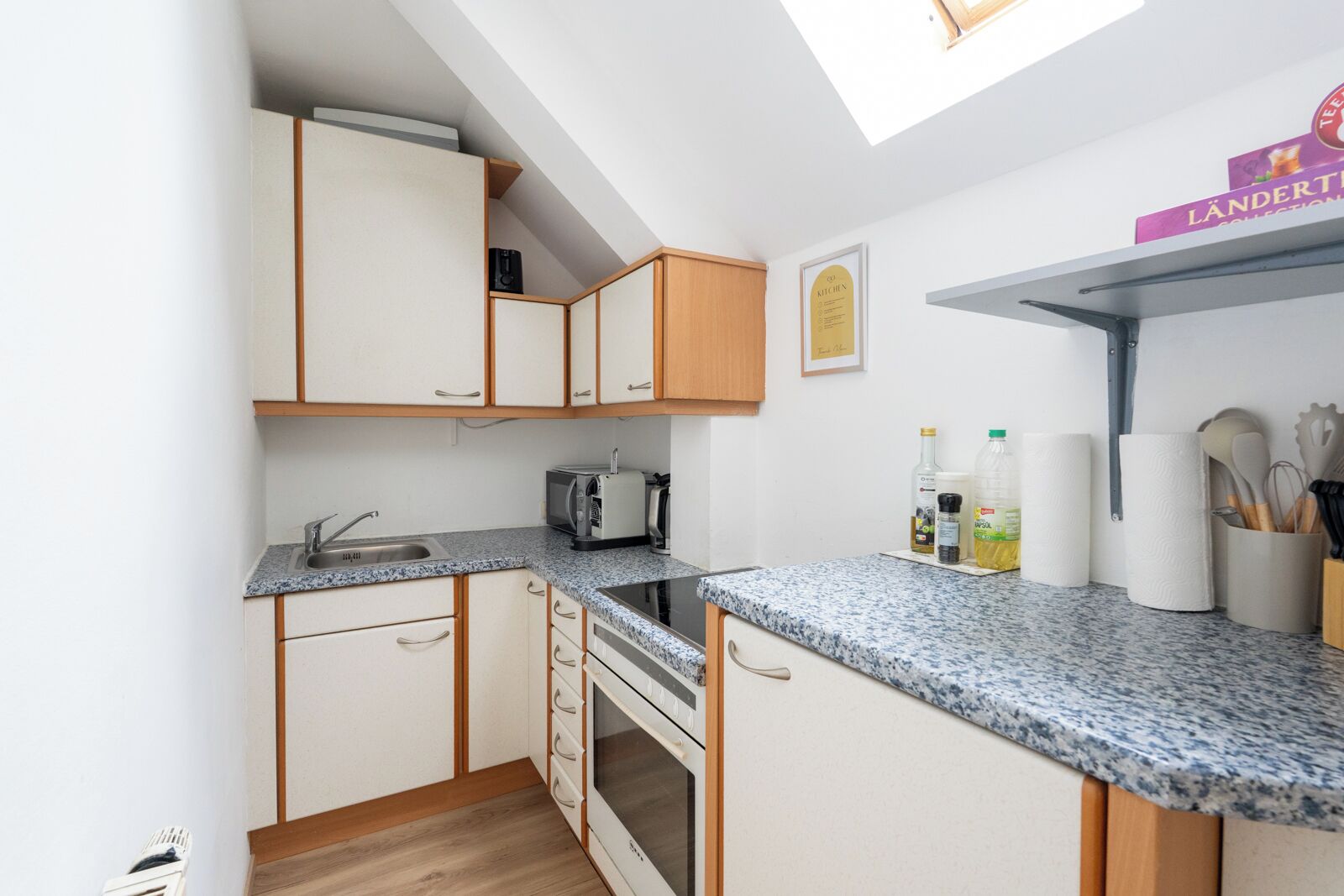 A compact kitchen with a microwave, toaster, and a small oven. There is a sink with a faucet, and a countertop with various kitchen items.