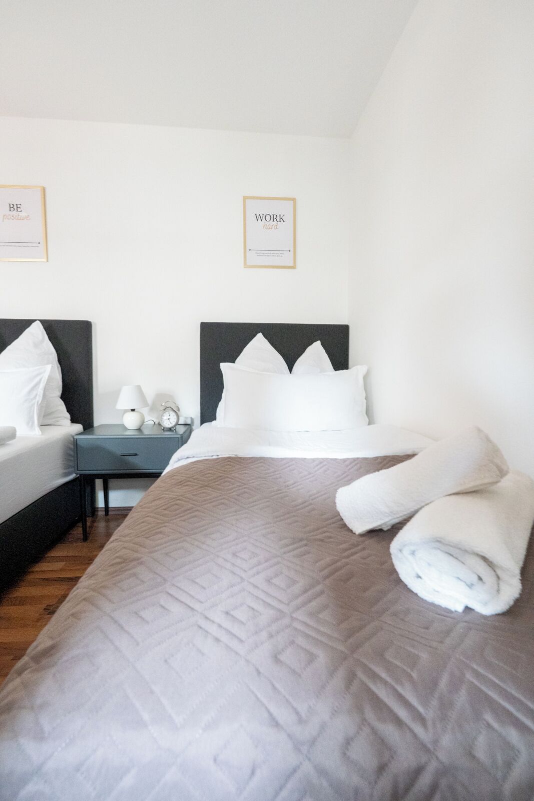 Una camera d'albergo con un letto, due comodini e due poster motivazionali appesi alla parete.