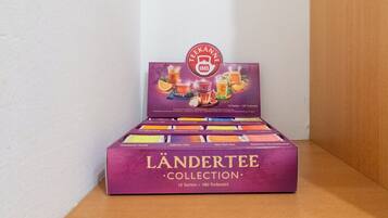 Una caja con varias cajas de té Ländertee Collection sobre una superficie de madera frente a una pared blanca.