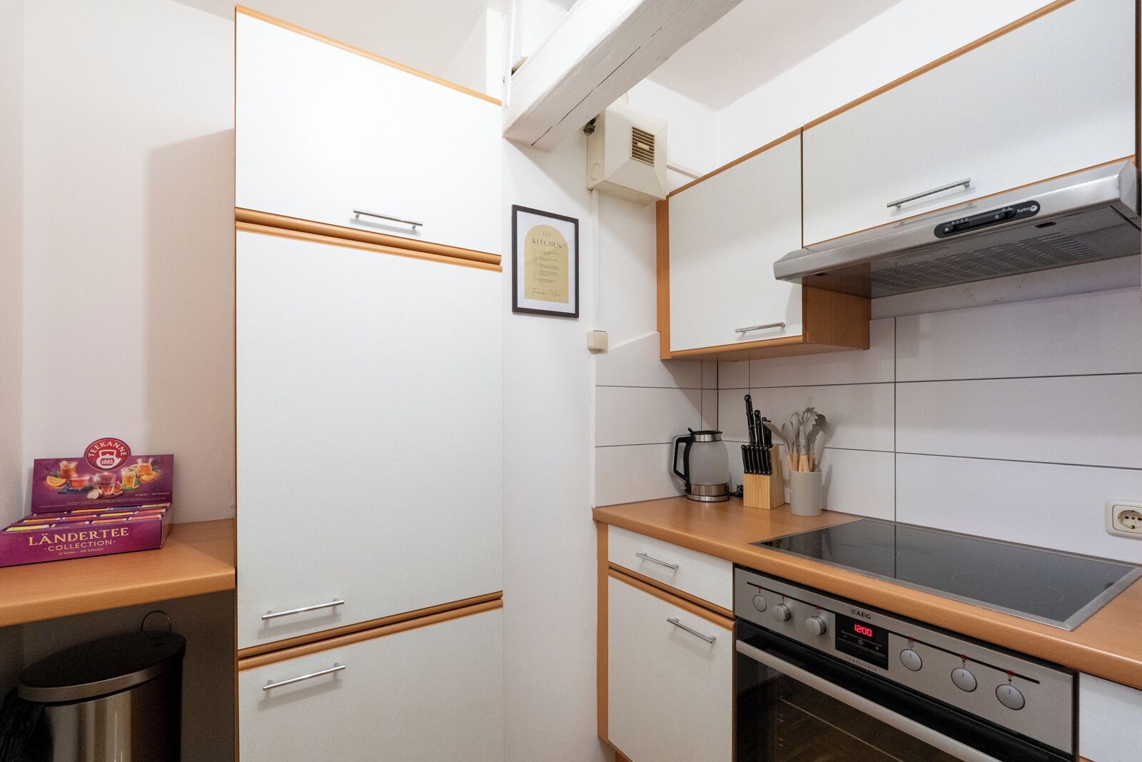 Cocina compacta con estufa, horno y una pequeña encimera con una cafetera y utensilios.