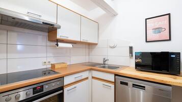 Una cocina moderna con armarios blancos, lavavajillas de acero inoxidable y microondas.